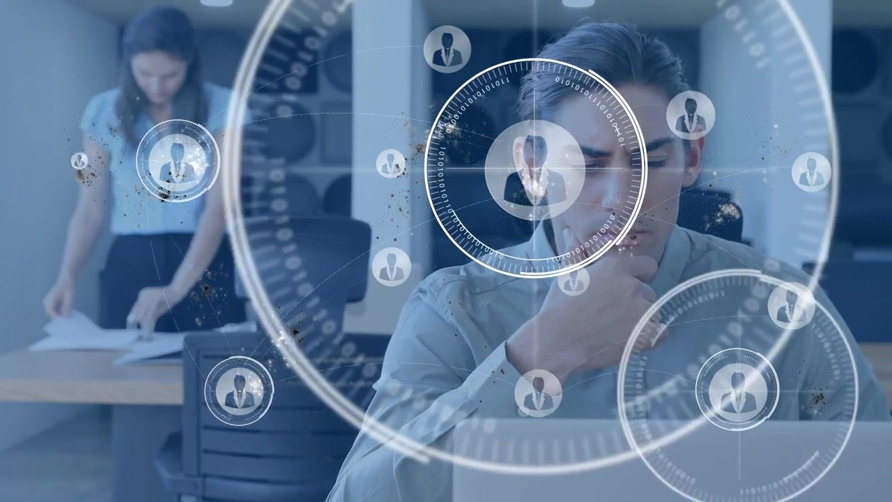 Uomo al laptop mentre un'amministratrice donna sistema documenti, con una sovrapposizione HUD in crescita che mappa i dati aziendali.