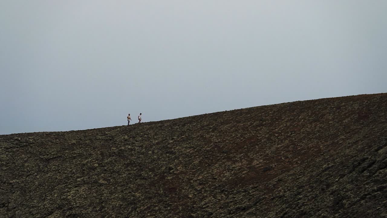dos hombres caminando en una montaña de volcán en cámara lenta