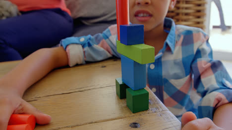 front view of little mixed-race boy playing with toys on table in a comfortable home 4k