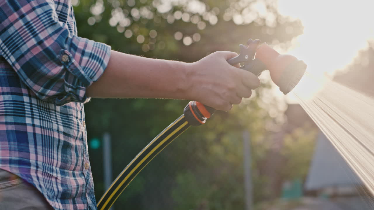 la mano del jardinero riega con una manguera de jardín usando una pistola de agua 1