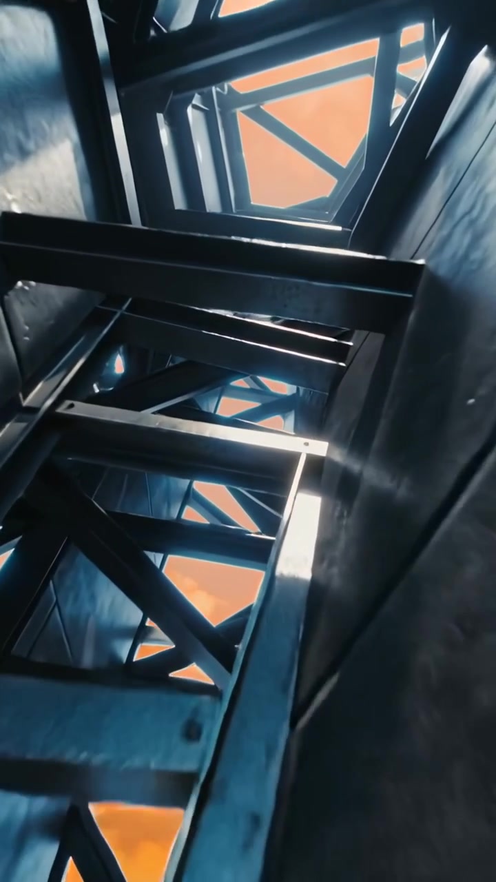 Vertical video: Tilting camera showing cross-braced steel shaft inside narrow core, with orange sky