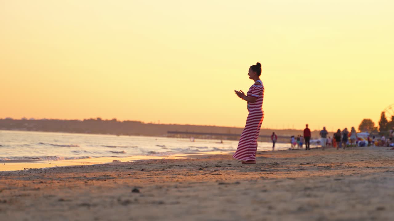 Woman walking barefoot on beach in the evening. Beautiful female in long dress walks on the sand shoreline at sunset. Summer vacation.