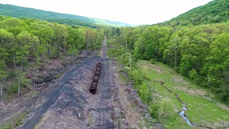 an aerial view of an abandoned narrow gauge coal rail road with rusting hoppers and freight cars and support building starting to be restored