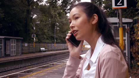 Businesswoman-using-phone-on-the-train-platform