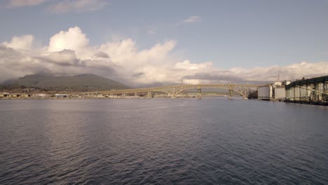 Drone-flying-over-Burrard-Inlet-waters-with-Ironworkers-Memorial-Bridge-in-background,-Vancouver-in-Canada