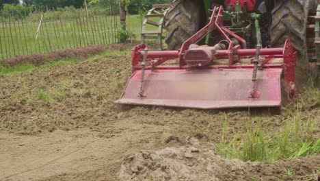 close up of red tractor plowing fertile land in a farm in india