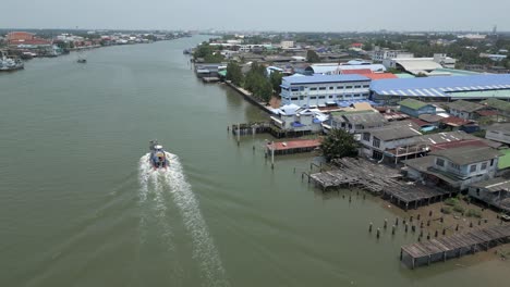 aerial view of a motorboat on a wide river with a riverside town