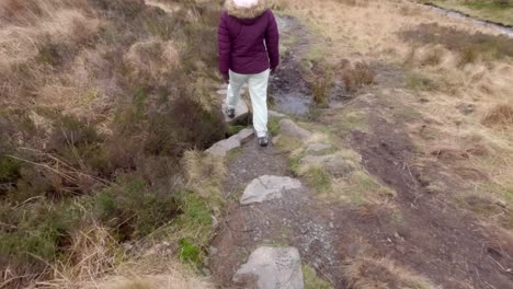 Tracking-shot-of-a-young-woman-navigating-around-the-muddy-walkway-on-the-Gray-Mares-Trail