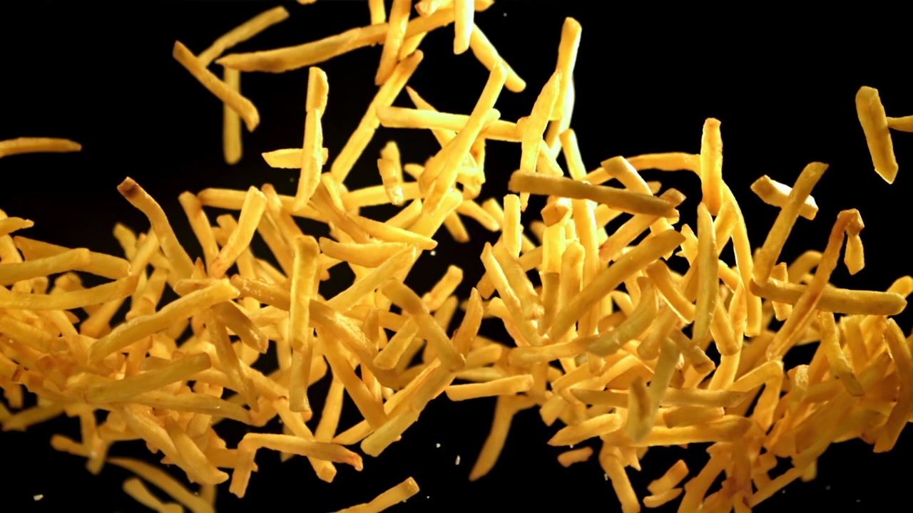 Patatine Fritte Dorate e Croccanti che Cadono al Rallentatore su Sfondo Nero