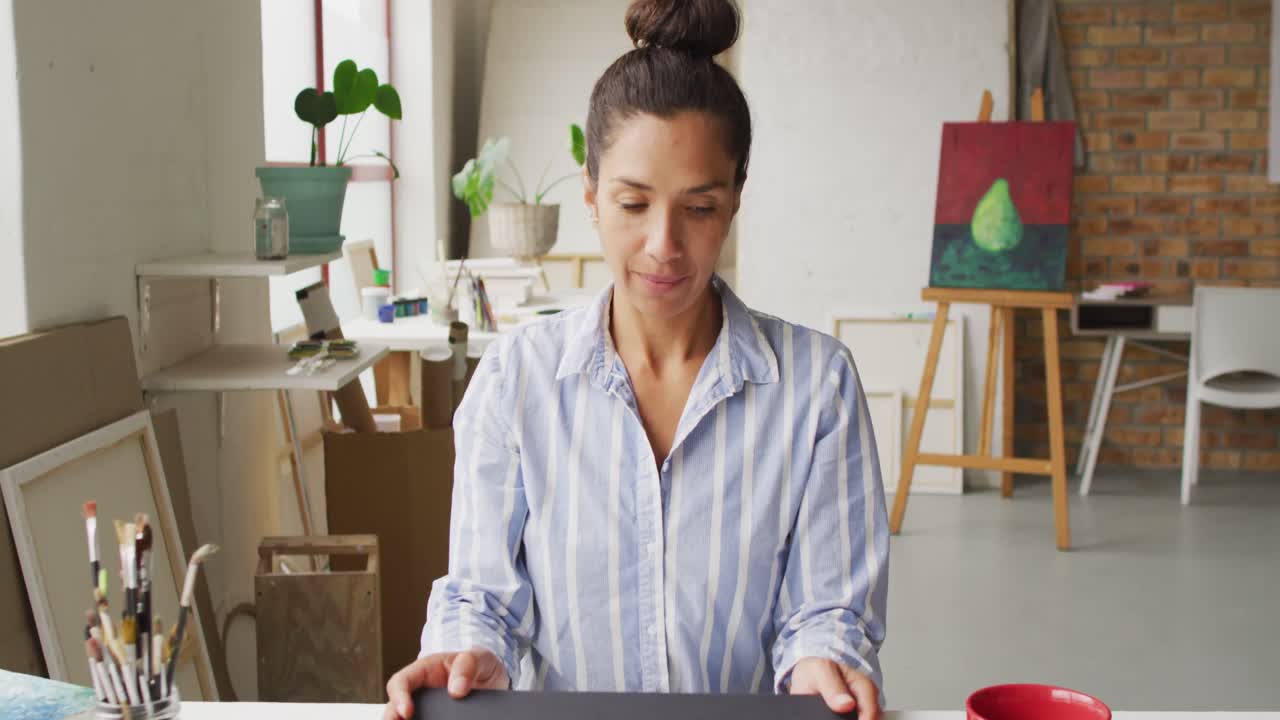 video de una feliz diseñadora biracial usando una computadora portátil en el estudio