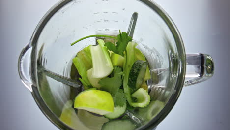 closeup green veggies falling blender in super slow motion. preparing vegan food