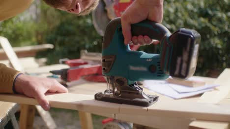 Focused craftsman saws the wood with a jigsaw