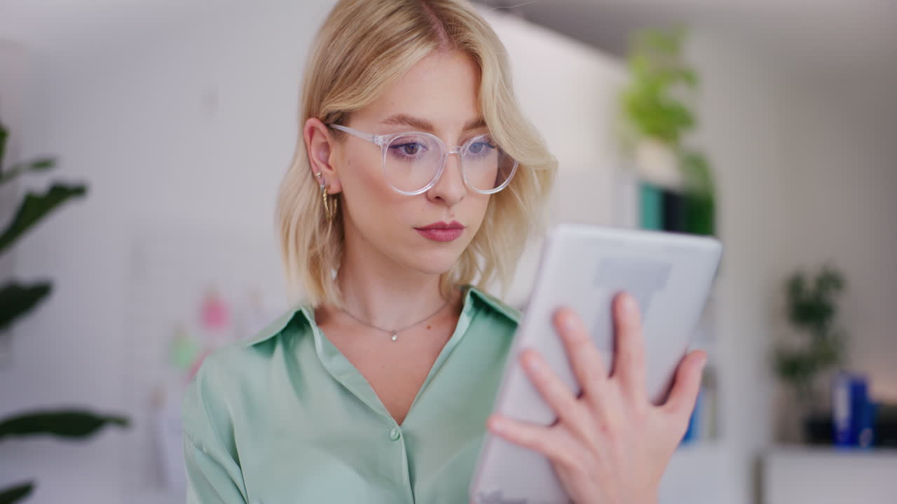 Businesswoman with Glasses Analyzes Sales Reports on Tablet
