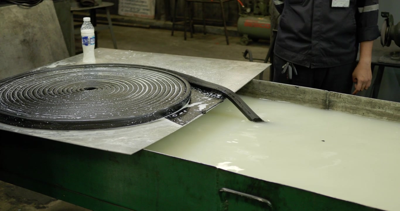 Dypning af en gummiliste til en bådkant i en opløsning inde i en fabrik i et industriområde i Bangkok, Thailand.