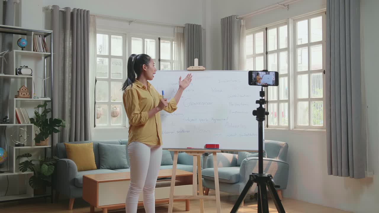 Asian Female Teacher With Marker Pen Shoots Video By Smartphone Camera While Teaching English At Home