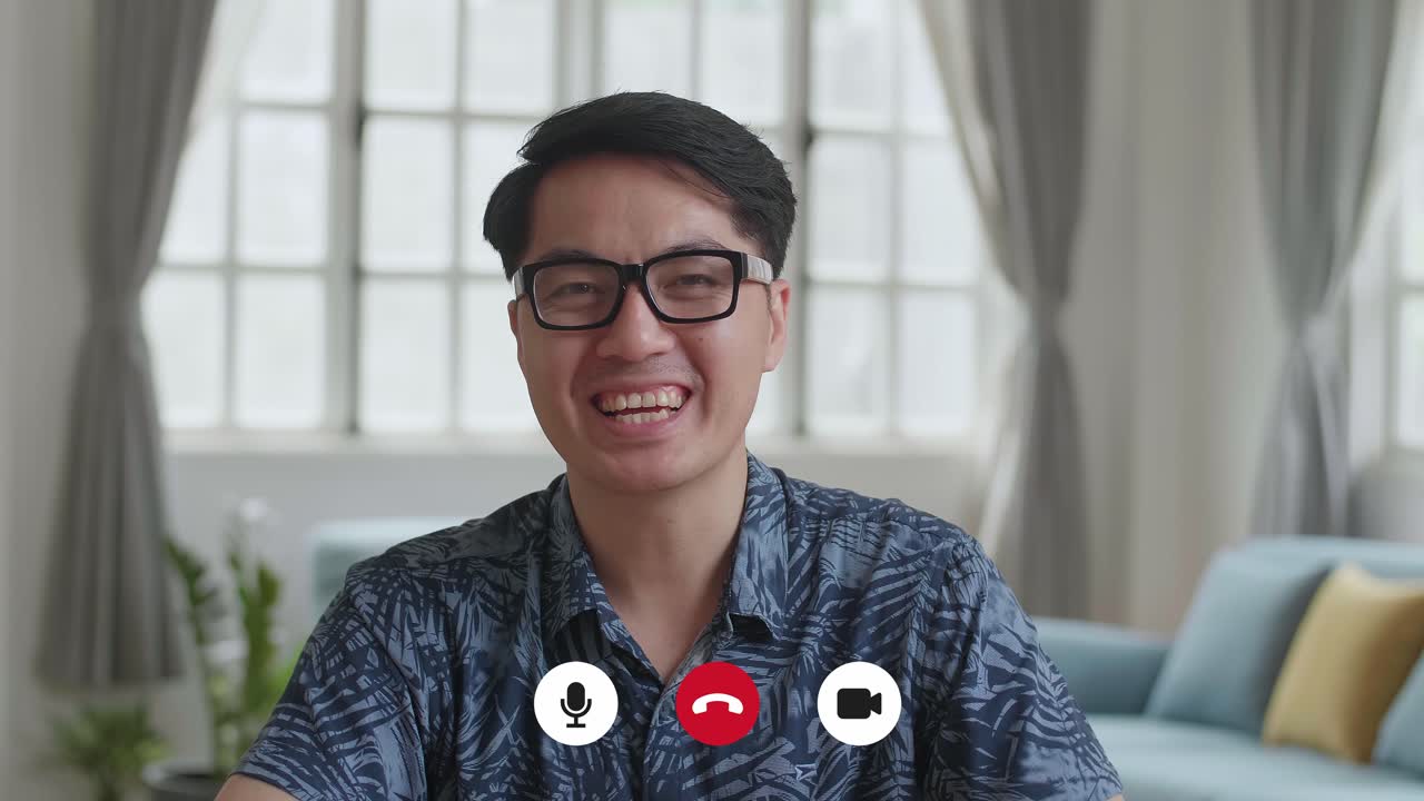 Uomo asiatico che parla alla telecamera nel salotto di casa, video in 4K
