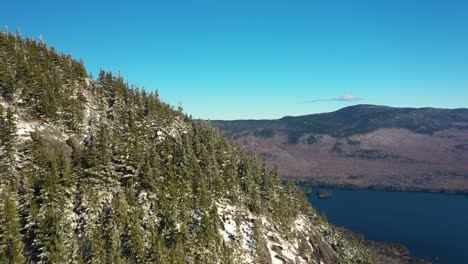 Aerial-footage-flying-past-a-snow-dusted-mountain-peak-to-reveal-a-blue-lake-and-more-mountains