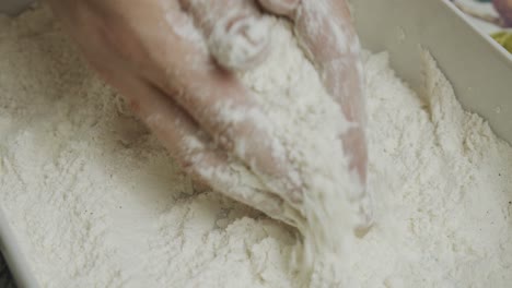 mixing chicken meat in cooking flour inside small ceramic plate