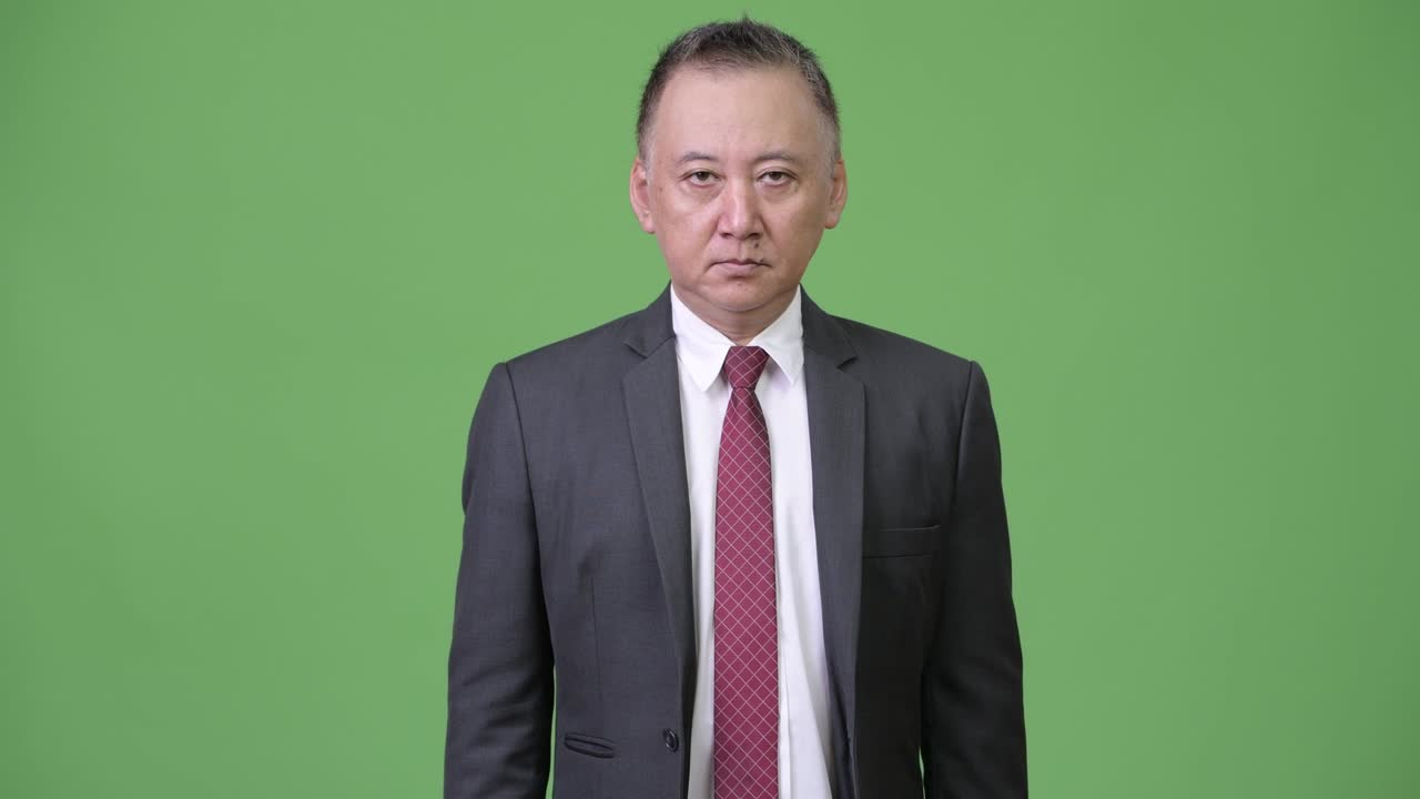 성숙 한 일본인 사업가 가 초록색 배경 에 악수 하고 있다