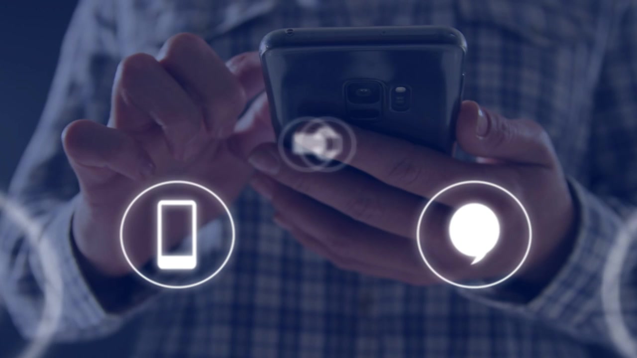 En voksen mand holder en telefon, tapper og swiper på lysende app-ikoner, der skifter og sløres, i en mobil demonstration.