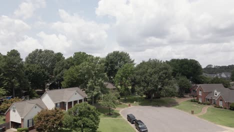 a drone zoom-in shot capturing a suburban neighborhood in the united states, showcasing tree-lined streets and residential houses. the greenery and -planned layout highlight the peaceful suburban