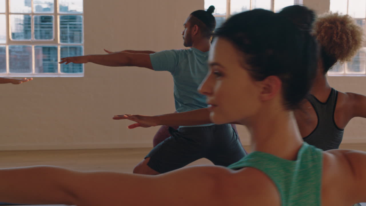 clase de yoga de jóvenes sanos practicando pose guerrera instructora mujer enseñando a grupos diversos disfrutando del estilo de vida físico haciendo ejercicio en el estudio al amanecer.