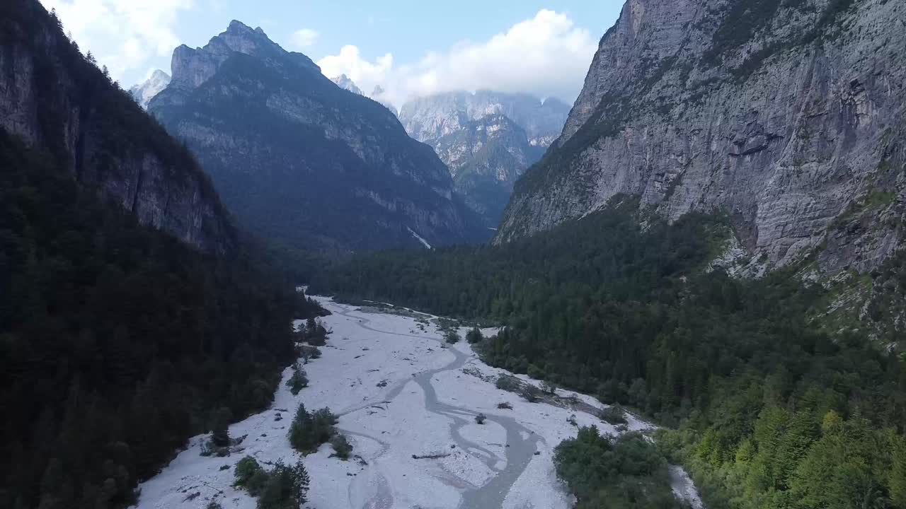 río seco y majestuosas montañas de los alpes, drone aéreo vuela hacia adelante vista