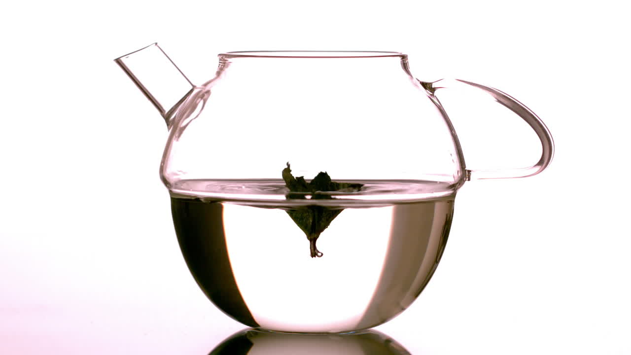 лист мяты падает в стеклянный чайник