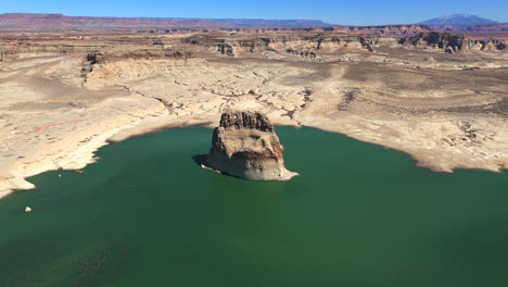 aerial view of lone rock - rock island in lake powell, surrounded by arid desert terrain in kane county, utah. pullback shot
