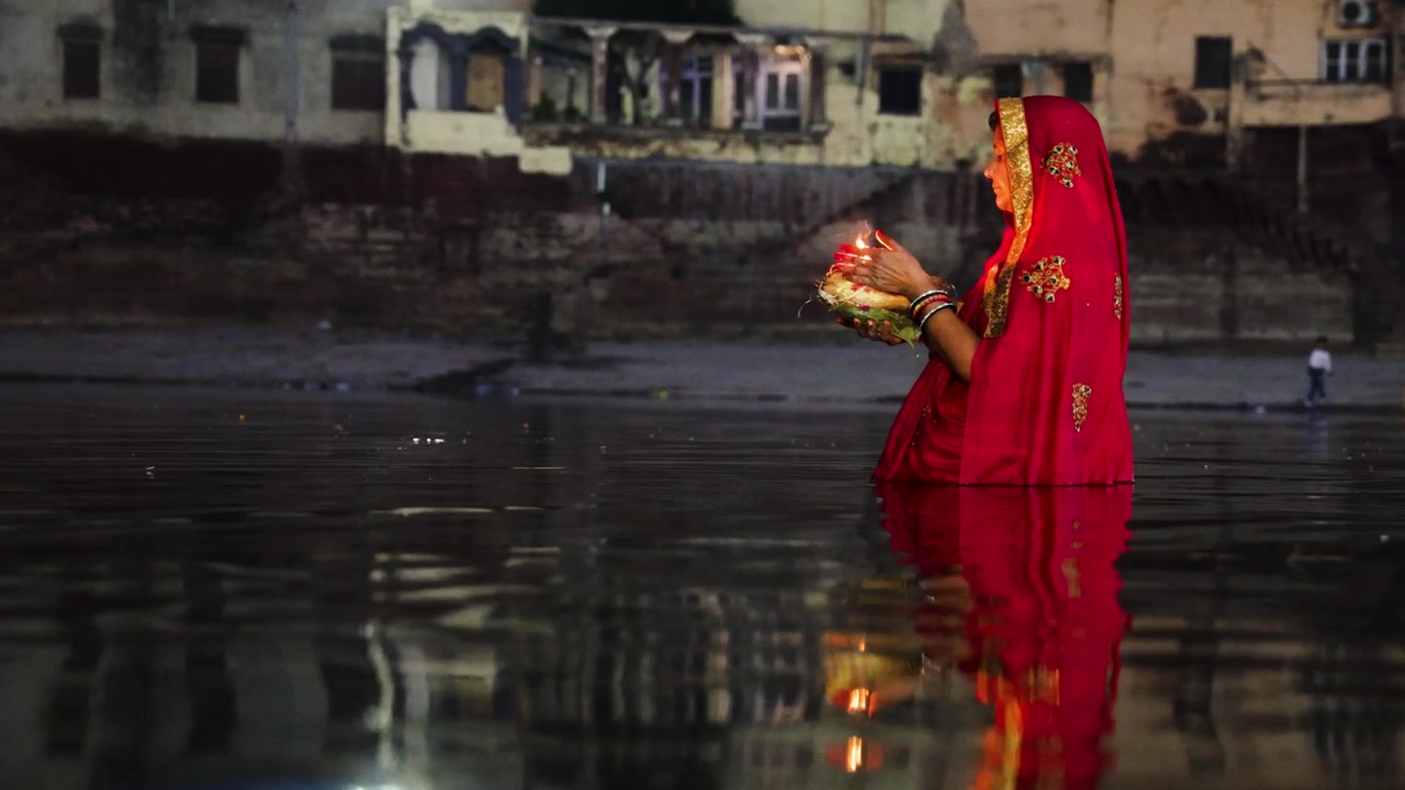 Cerimonia spirituale Chhath Puja con una donna che adora il Dio Sole con offerte di luce e preghiere sacre, ripresa durante il festival Chhath.