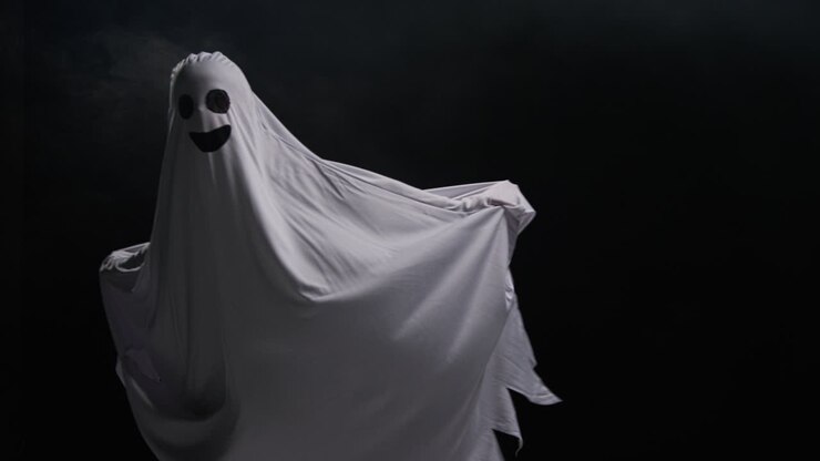 Child Dressed Up In Ghost Costume Trick Or Treating At Halloween Scaring People Running Around Against Black Background