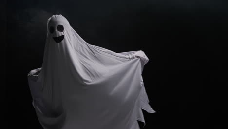 유령 의상을 입은 아이가 할로윈에 속임수를 입고 사람들을 겁내며 검은 바탕에 달리고 있습니다.