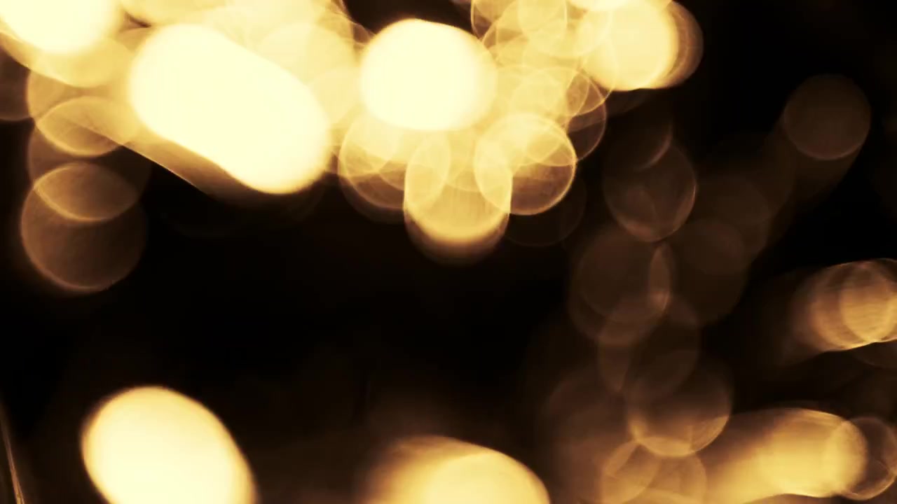 Particelle Bokeh Astratte di Luce Dorata Fluttuanti su Sfondo Nero