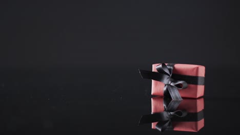 Video-of-gift-box-with-black-ribbon-and-copy-space-over-black-background