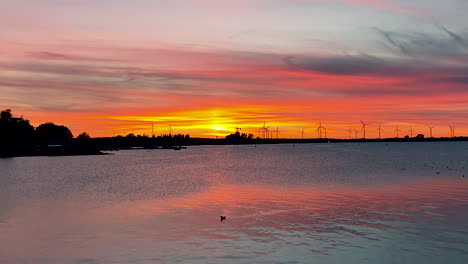 impresionante puesta de sol sobre el mar báltico en puck, polonia con molinos de viento en segundo plano
