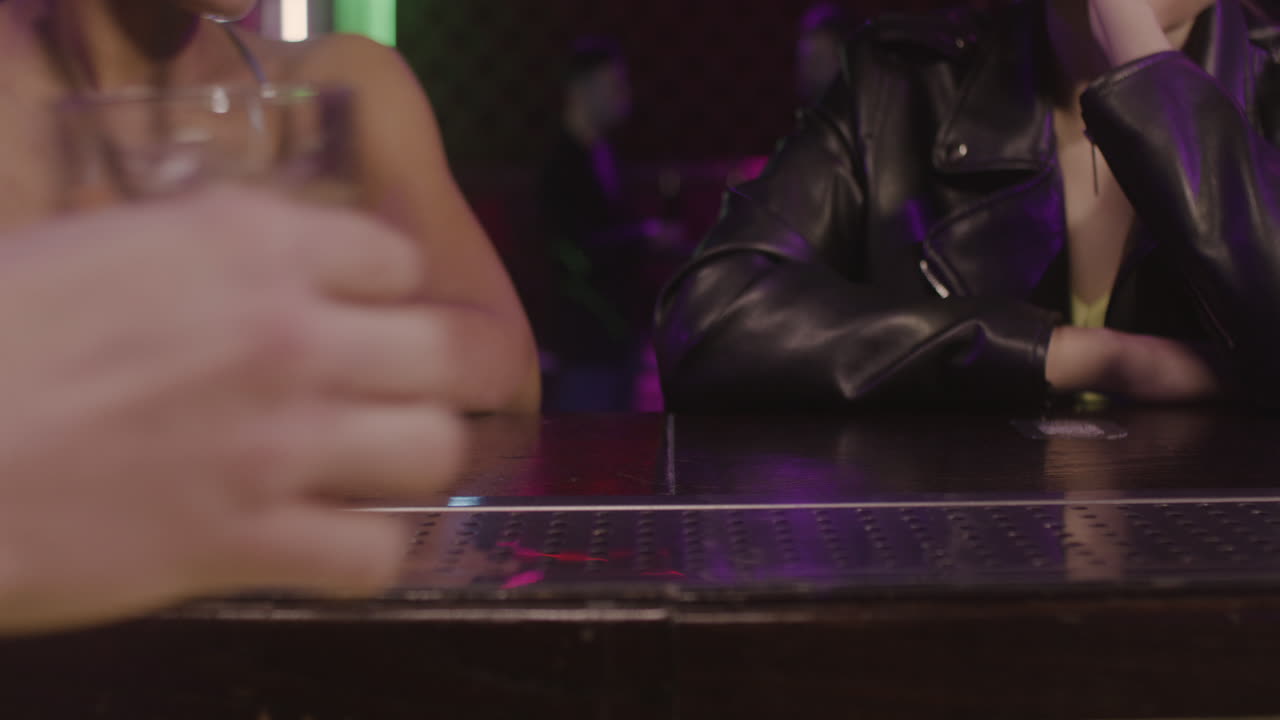 바 카운터 1에서 술을 마시고 서로 이야기하는 두 명의 다민족 소녀