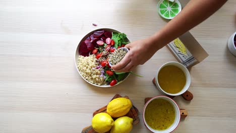 adding seeds to quinoa beets tomatoes salad plate