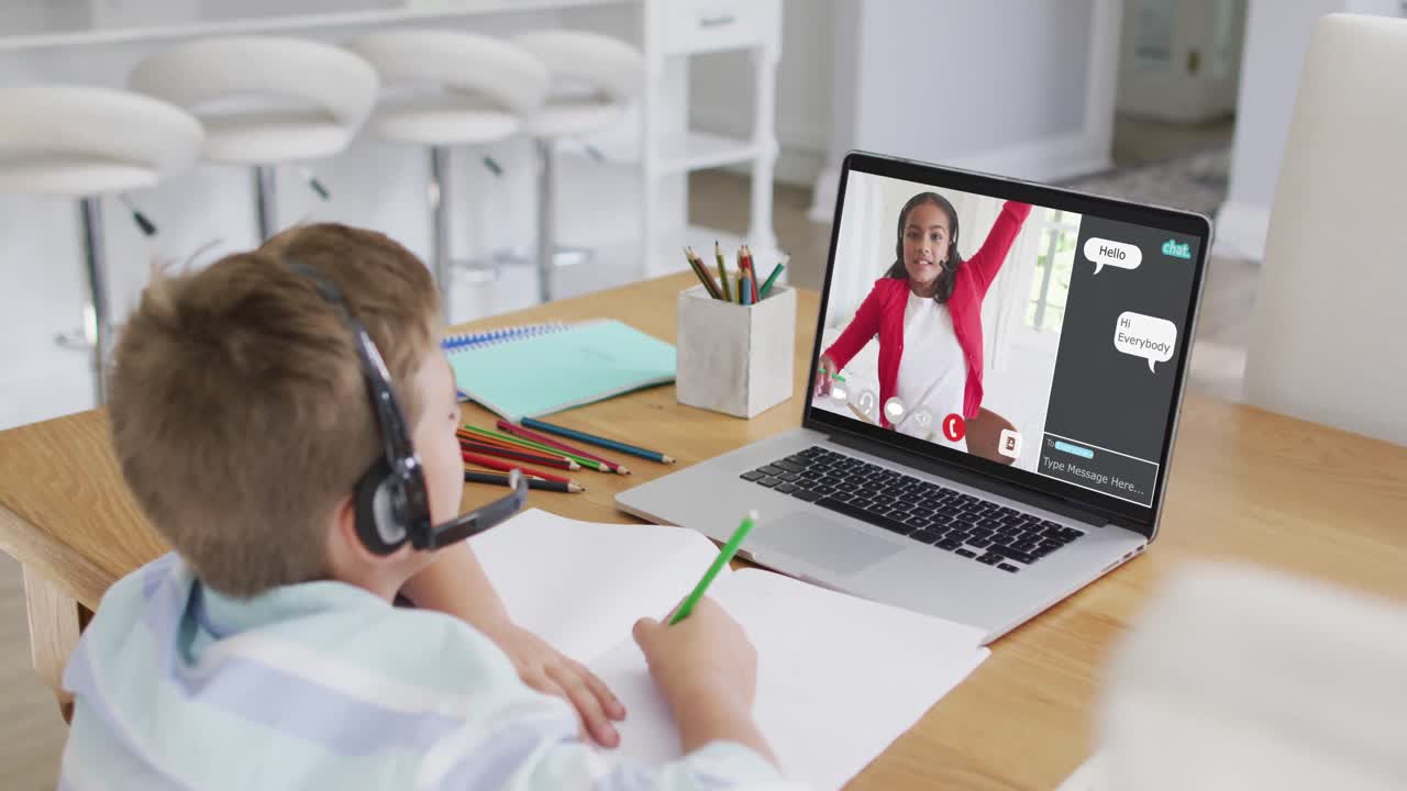 Schoolboy using laptop for online lesson at home, with school friend and web chat on screen
