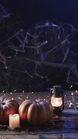 vertical video of halloween pumpkins, candles and smoke with copy space on blue background
