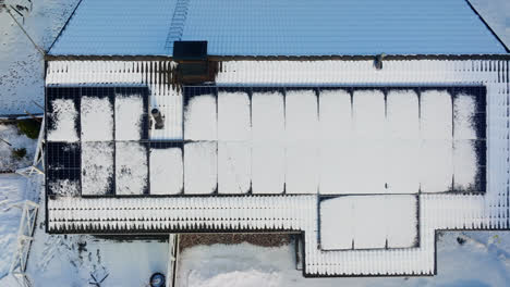 Aerial-overhead-shot-over-a-snowy-house-with-solar-cells-on-the-roof,-winter-day