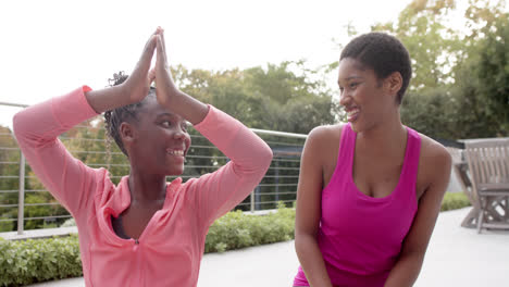 happy african american daughter and mother practicing yoga and smiling in garden, slow motion