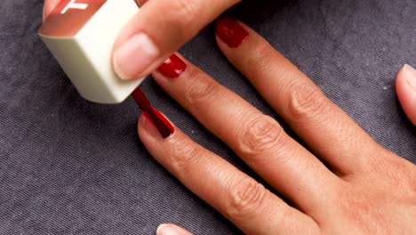 woman painting her nails with red nail polish