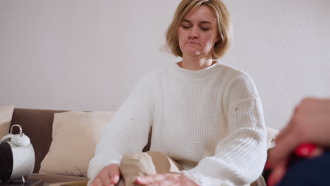 reflective woman seated on sofa with intense focus on her face while molding soft material on tray during therapy session, capturing emotional depth and mindfulness in calming indoor setting