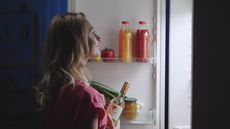 woman looking in a refrigerator at night