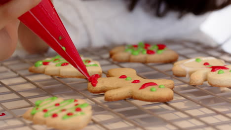 decorating christmas cookies with colorful icing on cooling rack at home