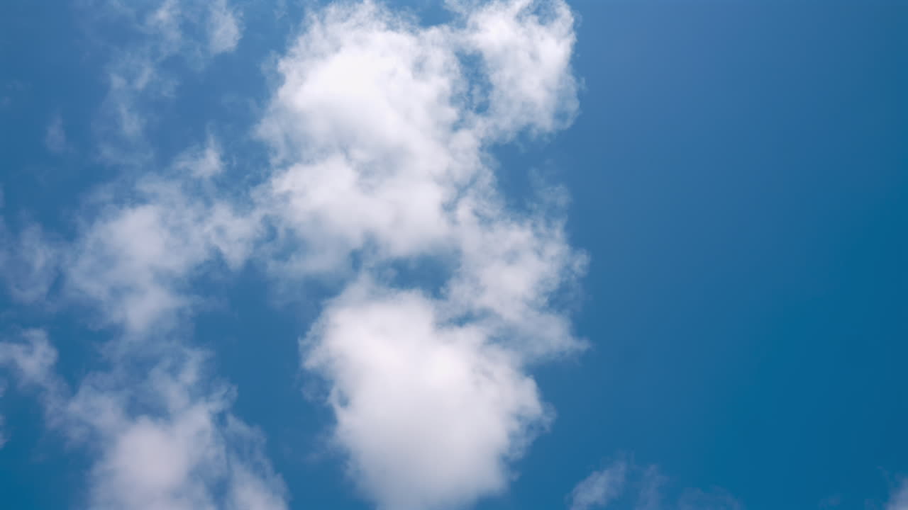 View of white, fluffy clouds moving on the blue sky