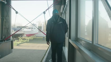 elderly man walks over the edge of a newly built ship at a shipyard to instruct a coworker