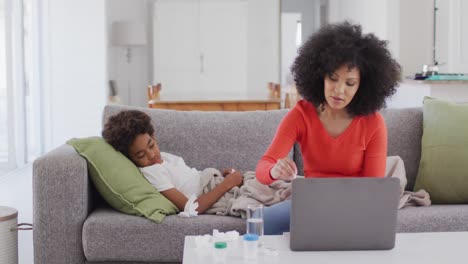 mother measuring temperature of her sick son at home
