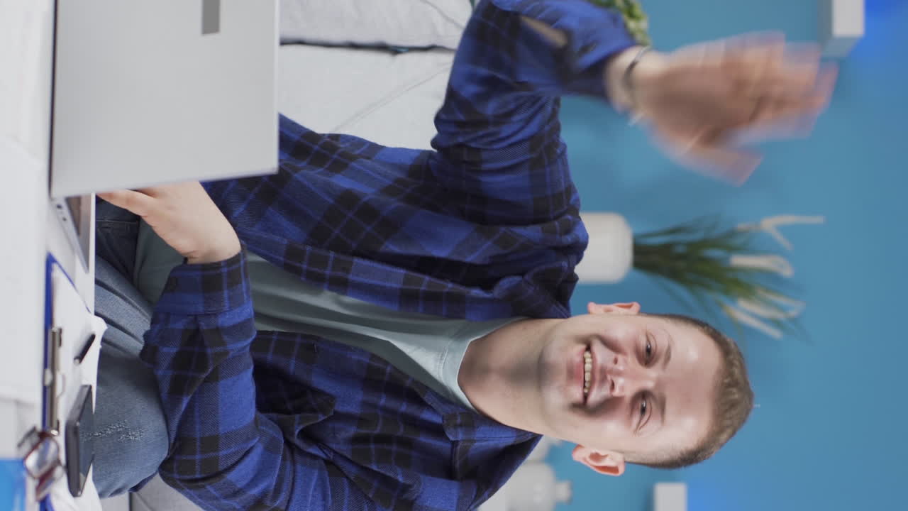 video vertical de un trabajador de oficina en casa saludando a la cámara.