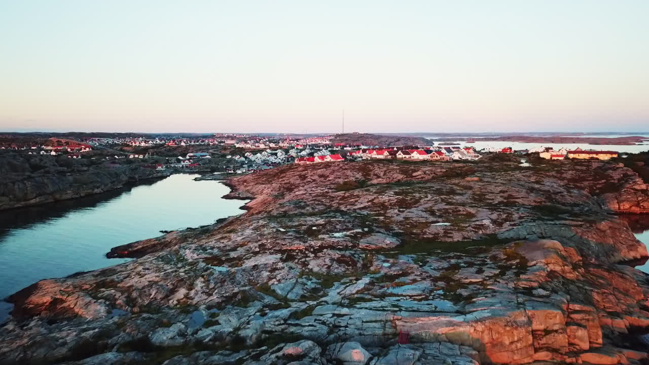 Drone lentää kohti taloa rantaviivalla meren äärellä auringonlaskun aikaan Ruotsissa.